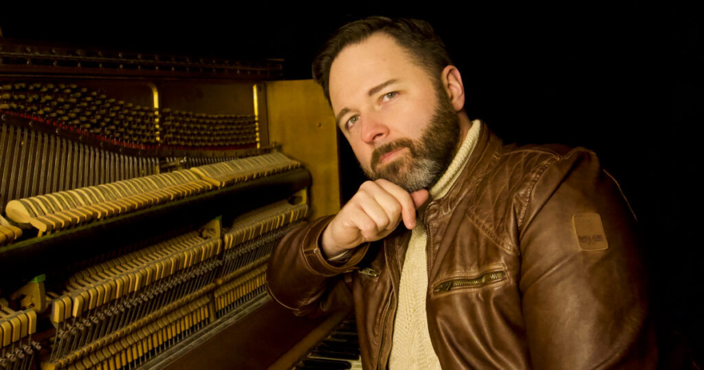 Musicien auteur compositeur interprète songeur assis à son piano.